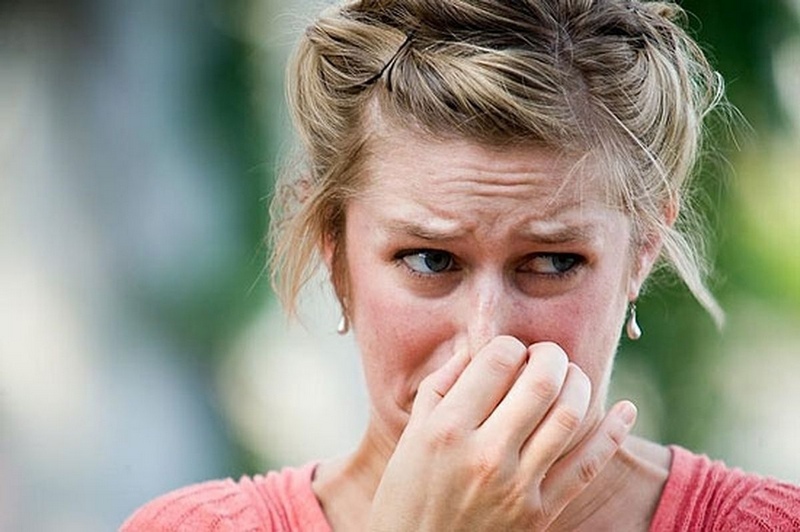Женщина закрывает нос от плохого запаха